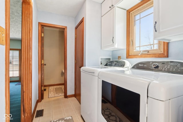 washroom featuring visible vents, cabinet space, baseboards, and washing machine and dryer