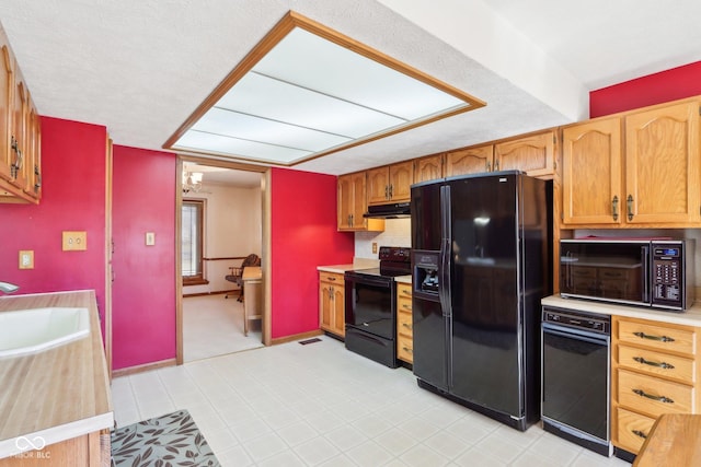 kitchen featuring visible vents, a sink, black appliances, light countertops, and under cabinet range hood