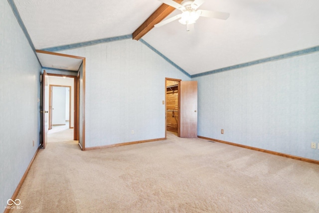 carpeted spare room featuring attic access, vaulted ceiling with beams, baseboards, and ceiling fan