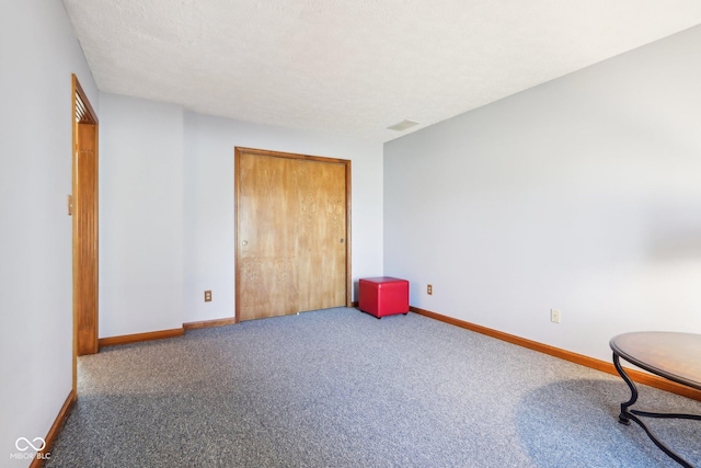 interior space featuring visible vents, a textured ceiling, a closet, carpet floors, and baseboards