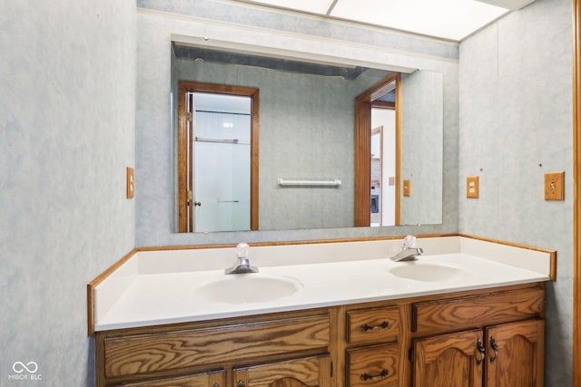 bathroom featuring a sink, double vanity, and wallpapered walls