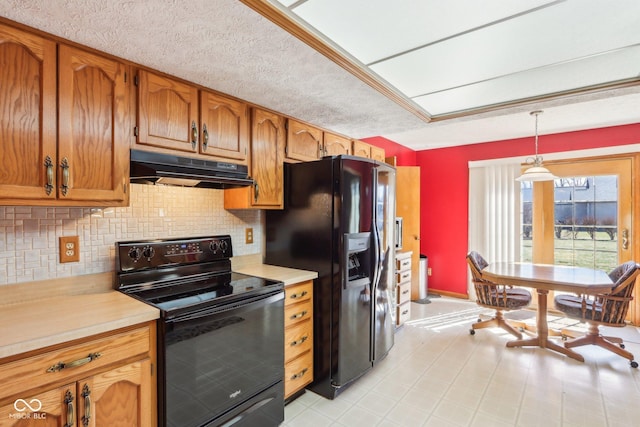 kitchen with black appliances, light countertops, brown cabinets, and under cabinet range hood