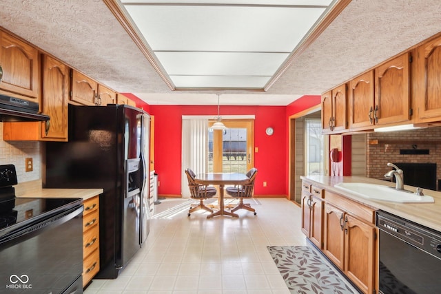 kitchen with black appliances, a sink, ventilation hood, brown cabinetry, and light countertops