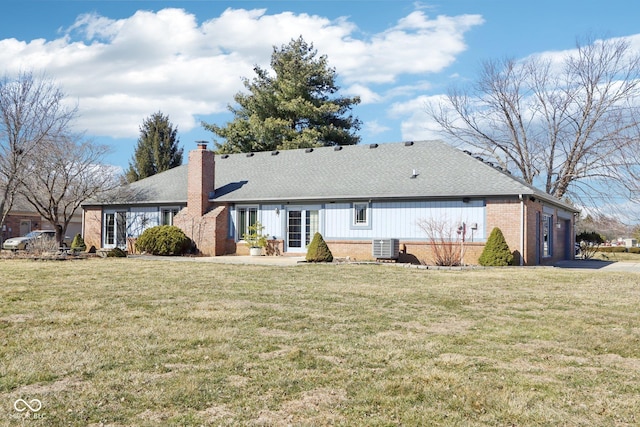 rear view of property featuring central air condition unit, a yard, an attached garage, brick siding, and a chimney