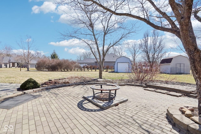 view of patio / terrace with an outdoor structure, a fire pit, and a detached garage