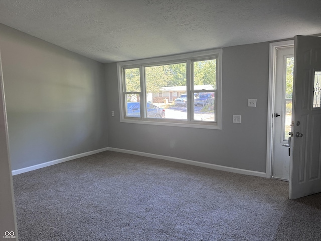 carpeted spare room featuring baseboards and a textured ceiling