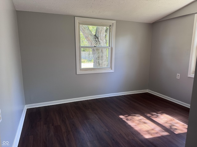 empty room featuring baseboards, dark wood-style flooring, and a textured ceiling