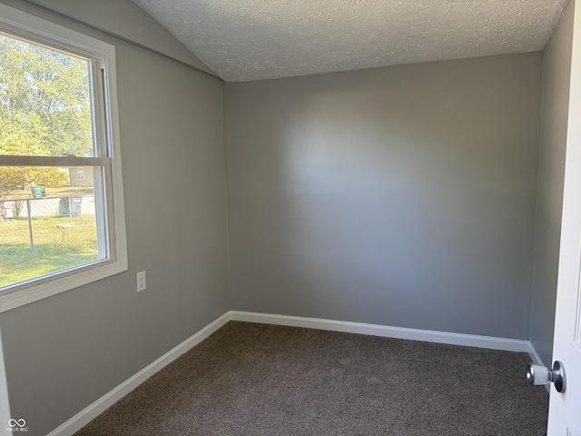 unfurnished room with dark colored carpet, plenty of natural light, lofted ceiling, and baseboards