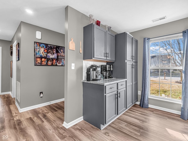 bar featuring visible vents, baseboards, light wood-style floors, and decorative backsplash