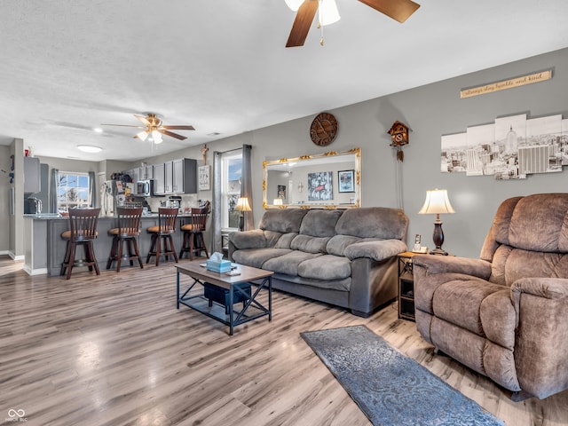 living area with wood finished floors, baseboards, and ceiling fan