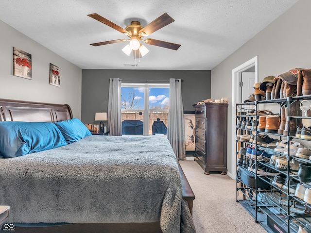 bedroom featuring light carpet, visible vents, a textured ceiling, and a ceiling fan