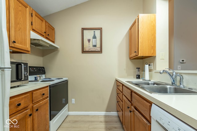 kitchen with white appliances, light countertops, under cabinet range hood, and a sink