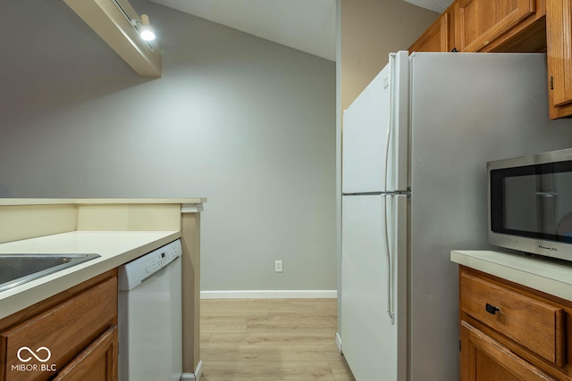 kitchen featuring light wood-style flooring, white appliances, brown cabinetry, light countertops, and baseboards