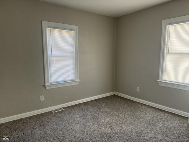 empty room featuring carpet, visible vents, and baseboards