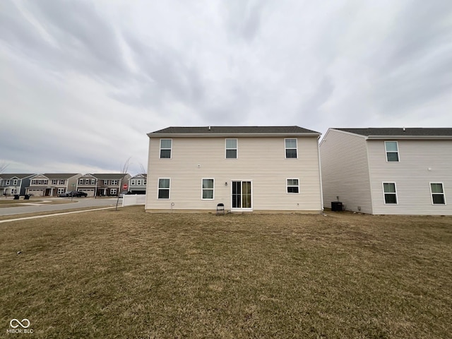 rear view of house featuring cooling unit and a yard