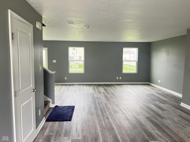 spare room with baseboards, plenty of natural light, wood finished floors, and stairs