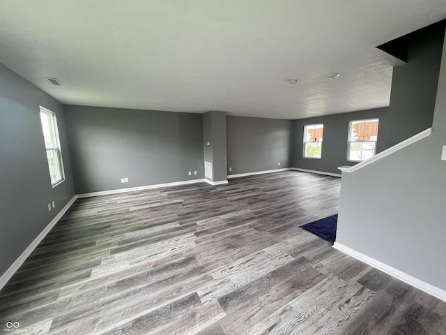 unfurnished living room featuring visible vents, baseboards, and wood finished floors