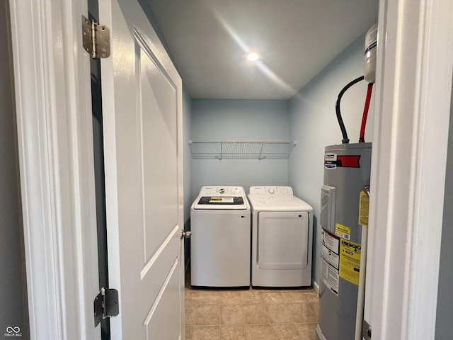 clothes washing area featuring electric water heater, light tile patterned floors, washing machine and clothes dryer, and laundry area