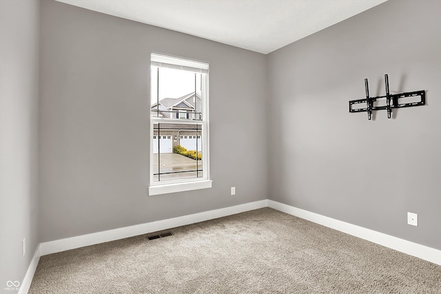 empty room with baseboards, visible vents, and carpet flooring