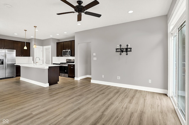 kitchen featuring open floor plan, light countertops, appliances with stainless steel finishes, and light wood-type flooring