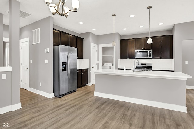 kitchen with stainless steel appliances, dark brown cabinets, and light wood-style flooring