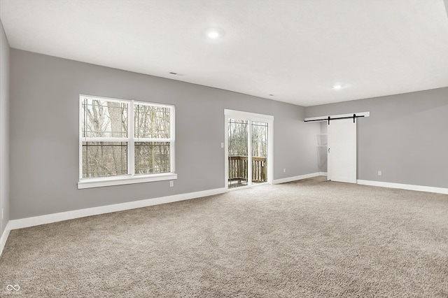 carpeted spare room with a barn door, baseboards, and recessed lighting