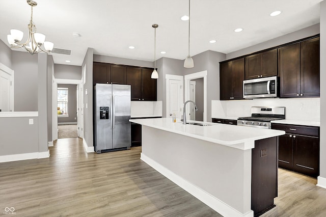 kitchen with light wood-type flooring, dark brown cabinetry, appliances with stainless steel finishes, and a sink