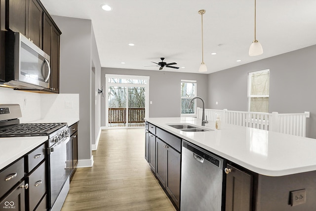 kitchen featuring a sink, light countertops, appliances with stainless steel finishes, light wood-type flooring, and an island with sink