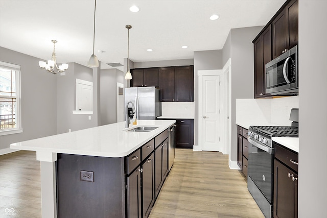 kitchen featuring light wood-type flooring, appliances with stainless steel finishes, light countertops, and a sink