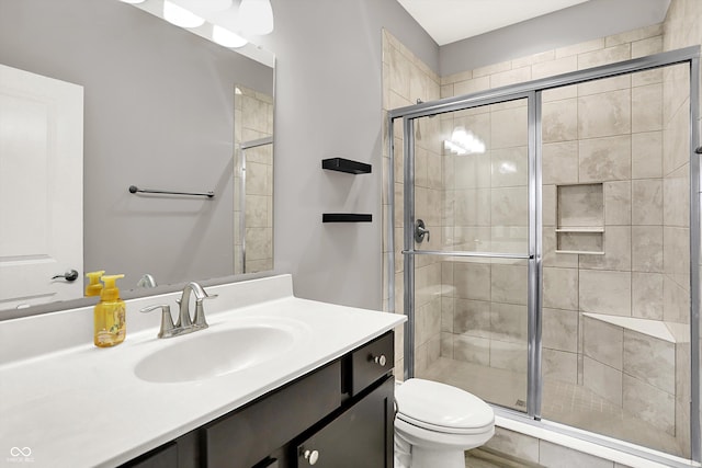 full bathroom featuring a stall shower, vanity, and toilet