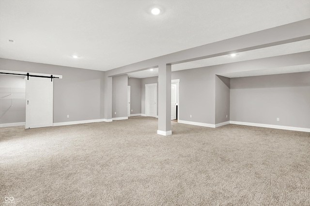 finished below grade area featuring carpet, recessed lighting, baseboards, and a barn door