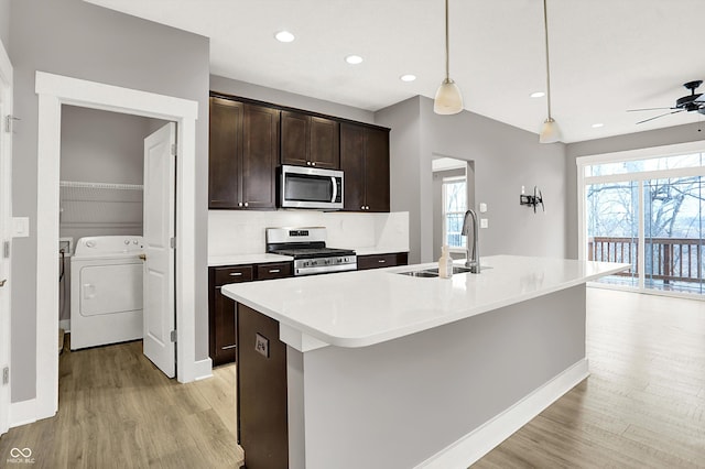 kitchen featuring washer / clothes dryer, appliances with stainless steel finishes, a sink, dark brown cabinets, and plenty of natural light