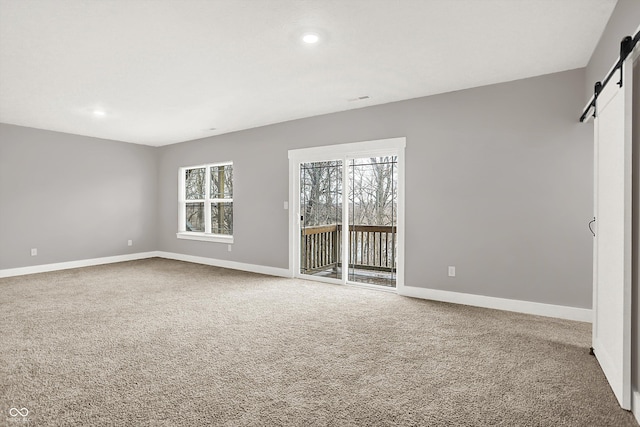 unfurnished room with carpet, a barn door, baseboards, and recessed lighting