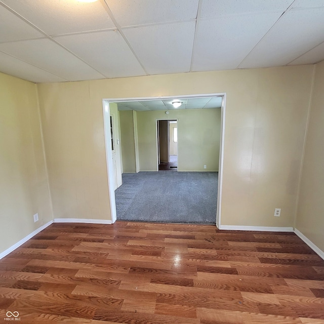 empty room with baseboards, wood finished floors, a paneled ceiling, and attic access