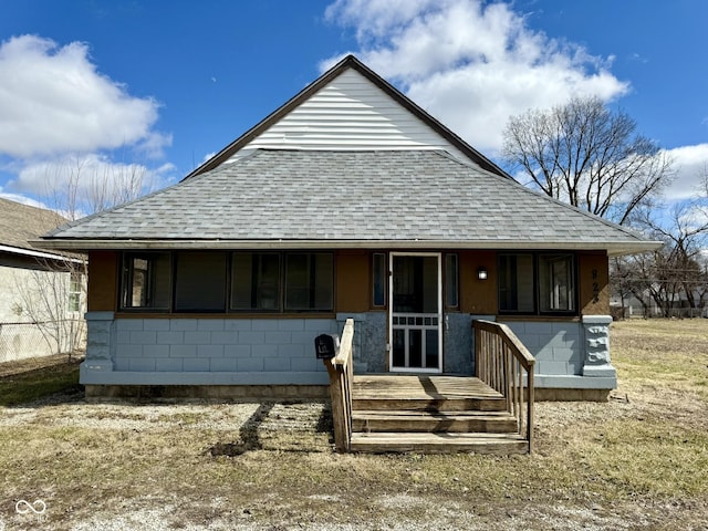 view of front facade with a porch, concrete block siding, and roof with shingles