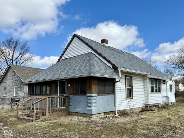 back of house featuring a shingled roof and a chimney