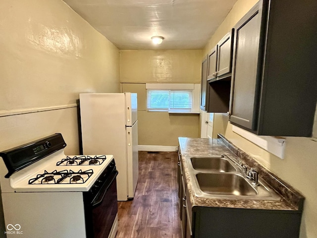 kitchen with freestanding refrigerator, dark wood finished floors, a sink, and gas range