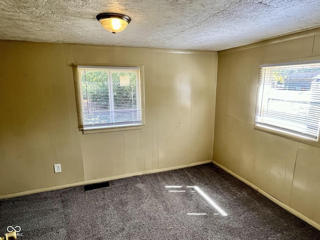 carpeted empty room with visible vents, a textured ceiling, and baseboards