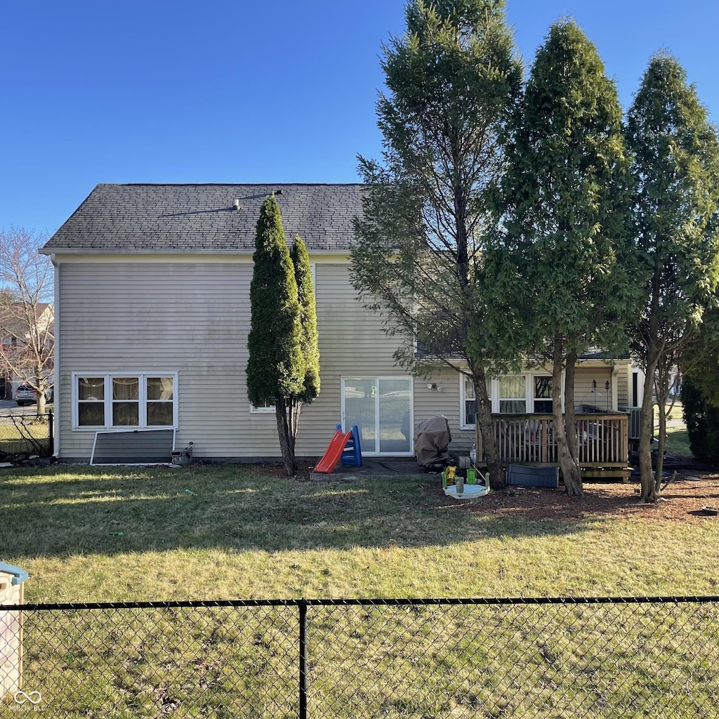 rear view of house featuring a deck, a yard, and fence
