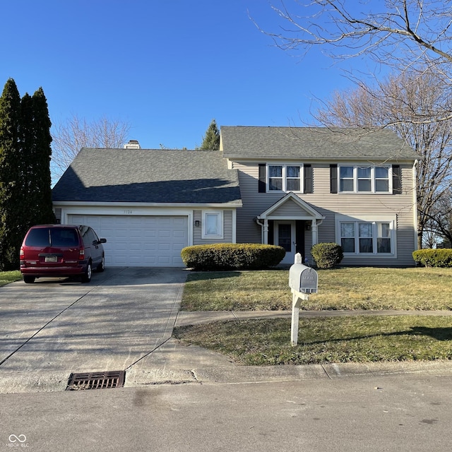 traditional-style home with driveway, a front yard, and a garage