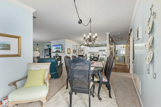 dining area featuring crown molding, a fireplace, visible vents, light carpet, and a chandelier