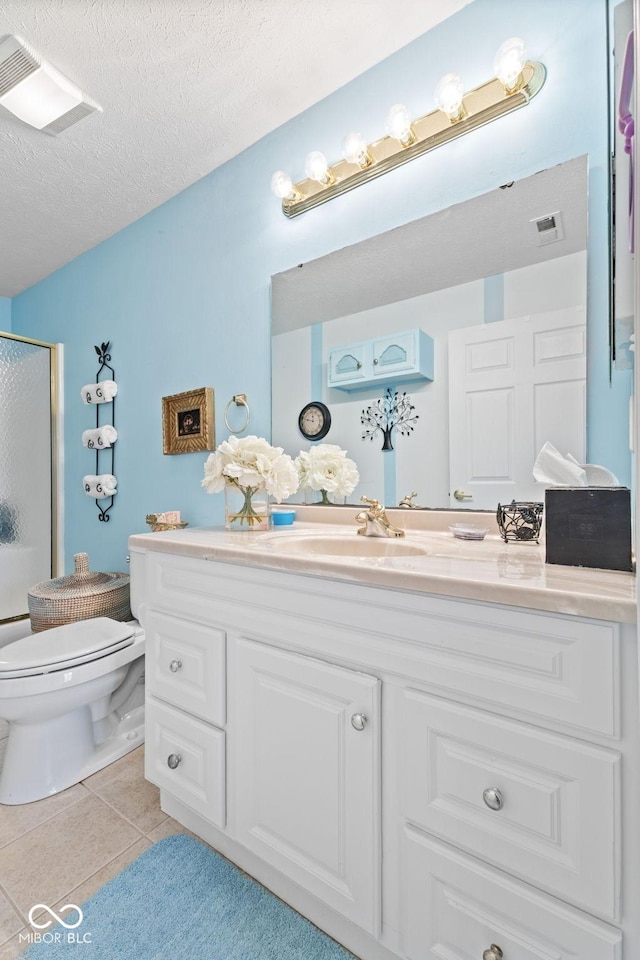 bathroom featuring toilet, a shower with shower door, a textured ceiling, vanity, and tile patterned floors