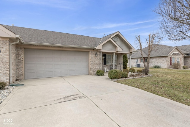 single story home with concrete driveway, roof with shingles, an attached garage, a front lawn, and brick siding