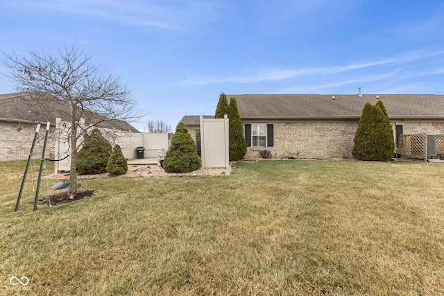 view of home's exterior with a yard, brick siding, roof with shingles, and fence