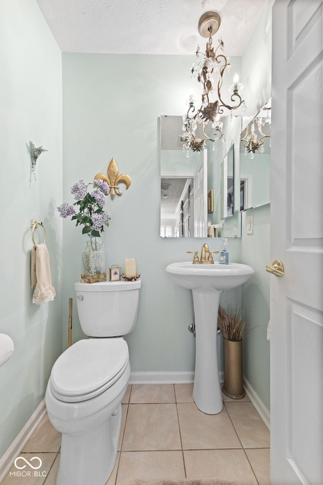 bathroom with a chandelier, baseboards, toilet, and tile patterned floors