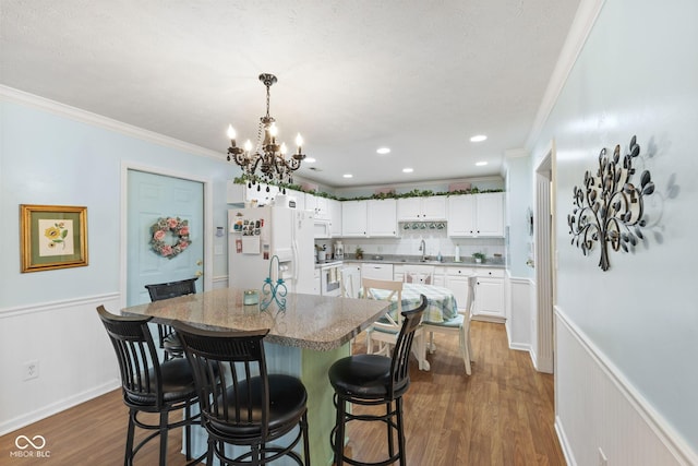 dining space with ornamental molding, dark wood-style flooring, and wainscoting