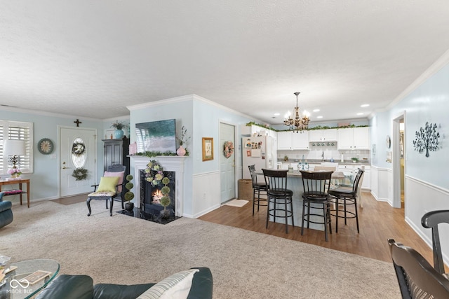 dining room featuring a fireplace with flush hearth, a notable chandelier, ornamental molding, and carpet flooring