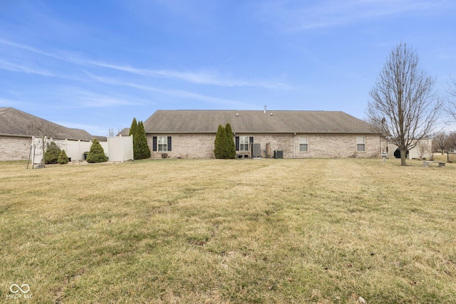 rear view of property featuring a lawn and fence