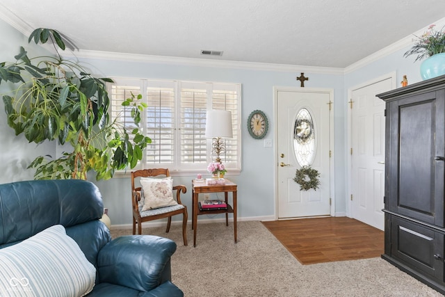 foyer featuring ornamental molding, visible vents, baseboards, and wood finished floors