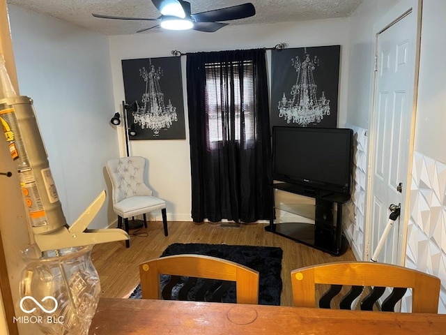 sitting room featuring ceiling fan with notable chandelier, a textured ceiling, and wood finished floors